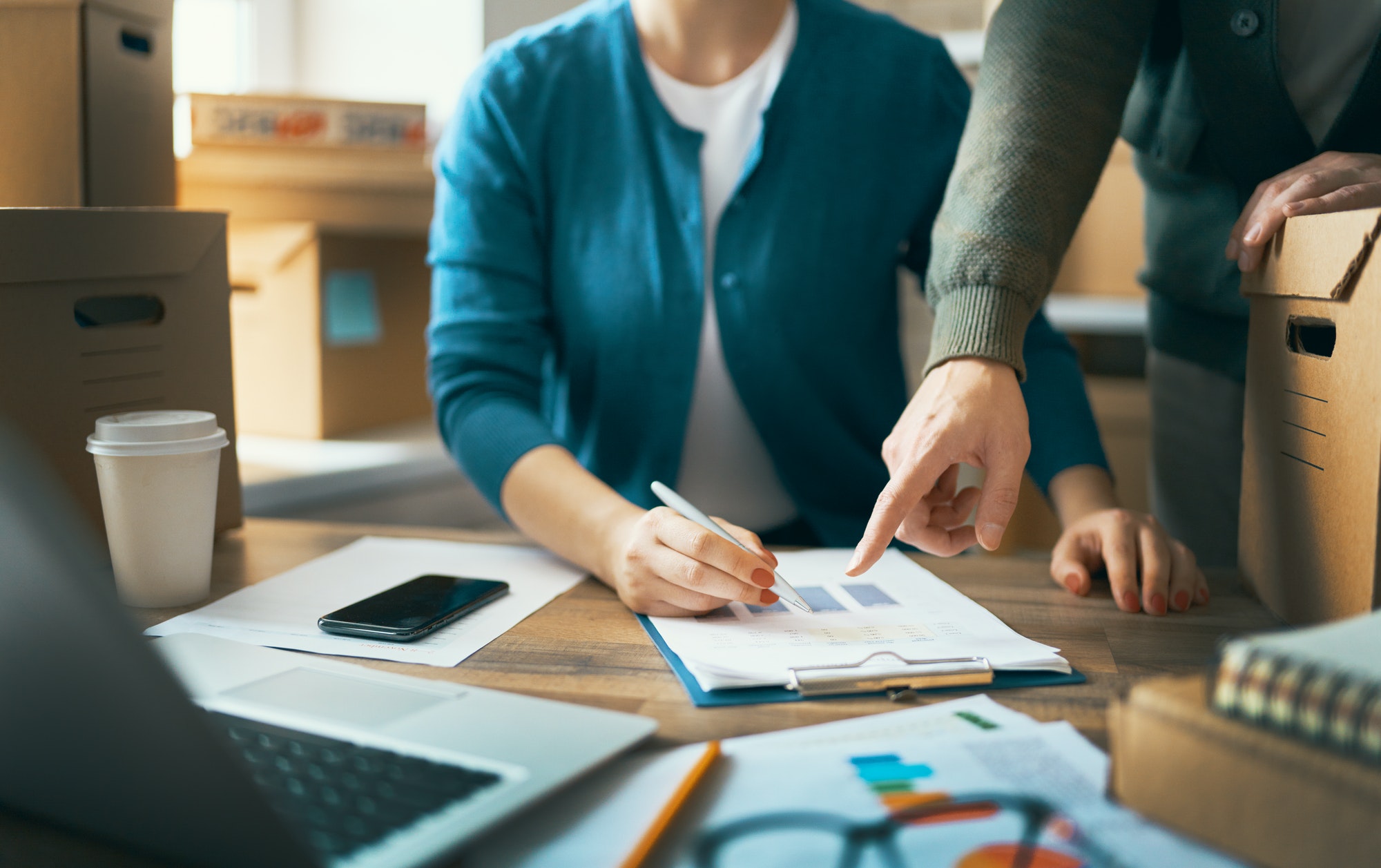 Two people reviewing shipping documents and a checklist beside cartons before warehouse receiving